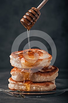 Pancakes are drizzled with honey. Dark background