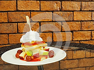 Pancakes with fresh fruits and whipped cream on glass table with