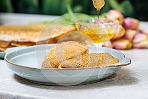 Pancakes with honey on a background of tulip flowers photo