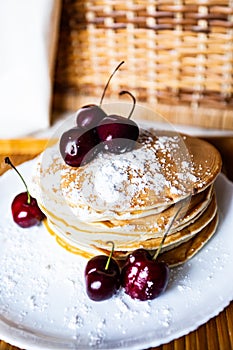 Pancakes with icing sugar and cherries