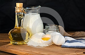 Pancakes ingredients. Milk egg flour oil sugar. Dark background