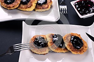 Pancakes with jam on 2 white plate. Dessert on dark background.