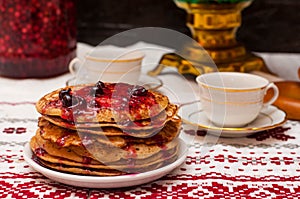 Pancakes with jam in the foreground, a copper samovar. Russian tea ceremony. two cups on a folk tablecloth