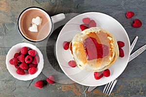 Love concept breakfast pancakes, hot chocolate and raspberries over slate