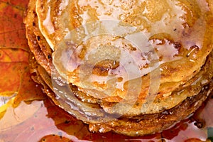 Pancakes with maple syrup on autumn multicolored leaves