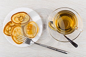 Pancakes with peach jam, tea in cup, spoon on saucer