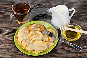 Pancakes in plate, bowl with honey, jam, milk and tea