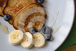 The pancakes on the plate are decorated with bananas, honey and blueberries, food and drink concept
