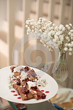 Pancakes on plate with decorations and flowers in vase photo