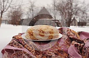 Pancakes on a plate in winter next to a Russian handkerchief, pancakes on a plate against the background of