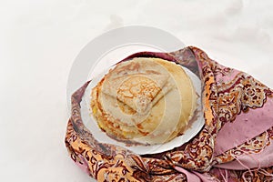Pancakes on a plate in winter next to a Russian handkerchief, pancakes on a plate against the background of