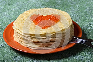 Pancakes with red caviar in the form of heart.