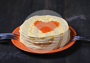 Pancakes with red caviar in the form of heart.