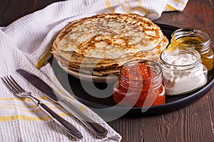 Pancakes with red caviar , sour cream and honey on black plate. Russian cuisine. Maslenitsa