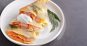 Pancakes with salmon, sour cream and greenstuff. photo