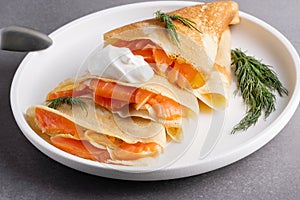 Pancakes with salmon, sour cream and greenstuff. Thin, not sweet blinchiki stuffed with red fish. Feast of Maslenitsa photo