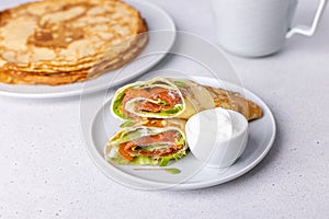 Pancakes with salmon (trout), sour cream and greenstuff. Thin, not sweet blinchiki stuffed with red fish. photo