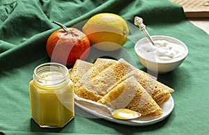 Pancakes served with fruit curd and sour cream, a traditional meal for Maslenitsa and Carnival.