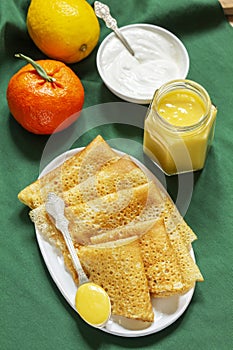 Pancakes served with fruit curd and sour cream, a traditional meal for Maslenitsa and Carnival.