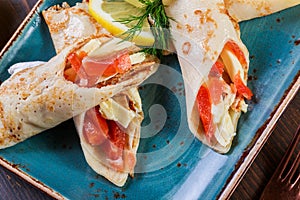 Pancakes with smoked salmon and cream cheese on plate close up.