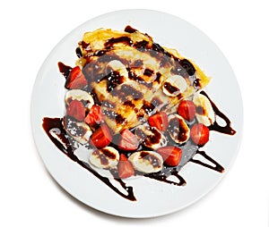 Pancakes with strawberry, banana and chocolate syrup on white