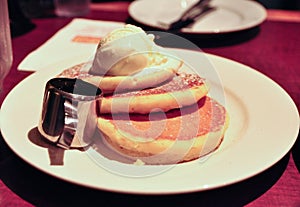 Pancakes with vanilla ice cream on a white plate.