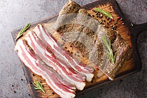 Pancetta Italian is a salt cured pork belly salume closeup on the wooden board. Horizontal top view photo