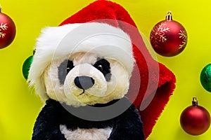 Panda Bear plush toy with Red Christmas Santa Hat surrounded by Colorful Vintage Ornaments on bright yellow background. Winter