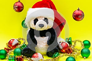 Panda Bear plush toy with Red Christmas Santa Hat surrounded by Tinsel Garland and Vintage Ornaments on bright yellow