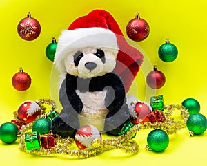 Panda Bear plush toy with Red Christmas Santa Hat surrounded by Tinsel Garland and Vintage Ornaments on bright yellow