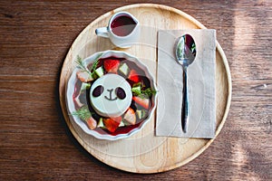 Pandacotta and strawberry syrup on a wood table