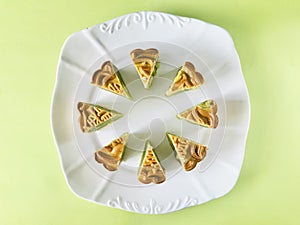 Pandan moon cake cut into eighths in white plate, green background.