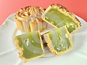 Pandan seeds moon cake with a portion cutout on red background. details.