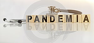 PANDEMIA the word on wooden cubes, cubes stand on a reflective white surface, on cubes - a stethoscope
