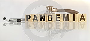 PANDEMIA the word on wooden cubes, cubes stand on a reflective white surface, on cubes - a stethoscope photo