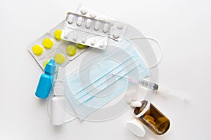 Pandemic of coronavirus.  Protective surgical mask,spray, pills, drops and syringe on white background. photo