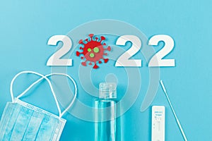 Pandemic coronavirus year 2022. Antigen test with mask and gel on blue fodo. Flat lay