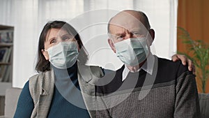 pandemic, elderly couple in medical masks use modern technologies and communicate with attending physician online via