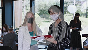 Pandemic safety at workplace. Happy young multiethnic colleagues looking at camera wearing face masks at modern office.