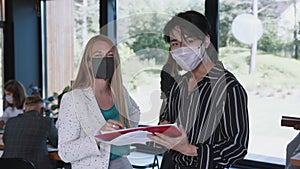 Pandemic safety at workplace. Happy young multiethnic colleagues looking at camera wearing face masks at modern office.