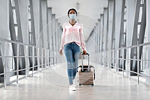 Pandemic Travel Concept. Young African Woman Wearing Medical Mask Walking In Airport