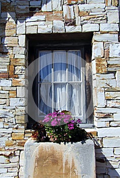 6 pane window and built in flower pot in house made from beige slate rocks photo