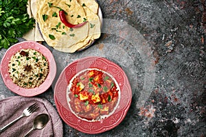 Paneer Makhani, Jeera Rice and paratha in pink plate on dark background