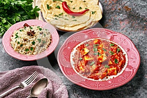 Paneer Makhani, Jeera Rice and paratha in pink plate on dark background