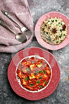 Paneer Makhani and jeera rice in pink plates on dark background