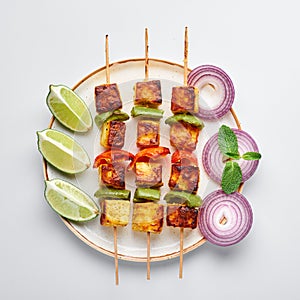 Paneer Tikka at skewers in white plate isolated at white background. Paneer tikka is an indian cuisine dish. Indian Food