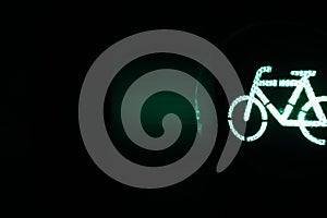 panel with copy space for text showing traffic light with green bicycle symbol at night in dark surrounding