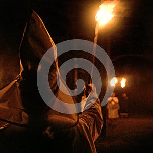 Panhandle, Florida, United States - circa 1995 - Ku Klux Klan KKK Night Ceremony Members in White Robes, Hoods burning torches