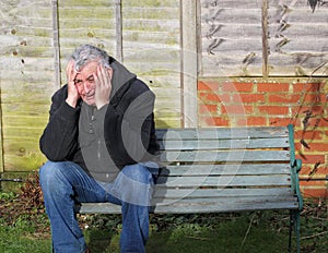 Panic attack man crying on a bench.