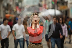 Panic attack in public place - woman covers his eyes.